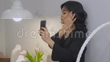 美丽的黑发女人用智能手机拍下了自己戴着新项链的照片